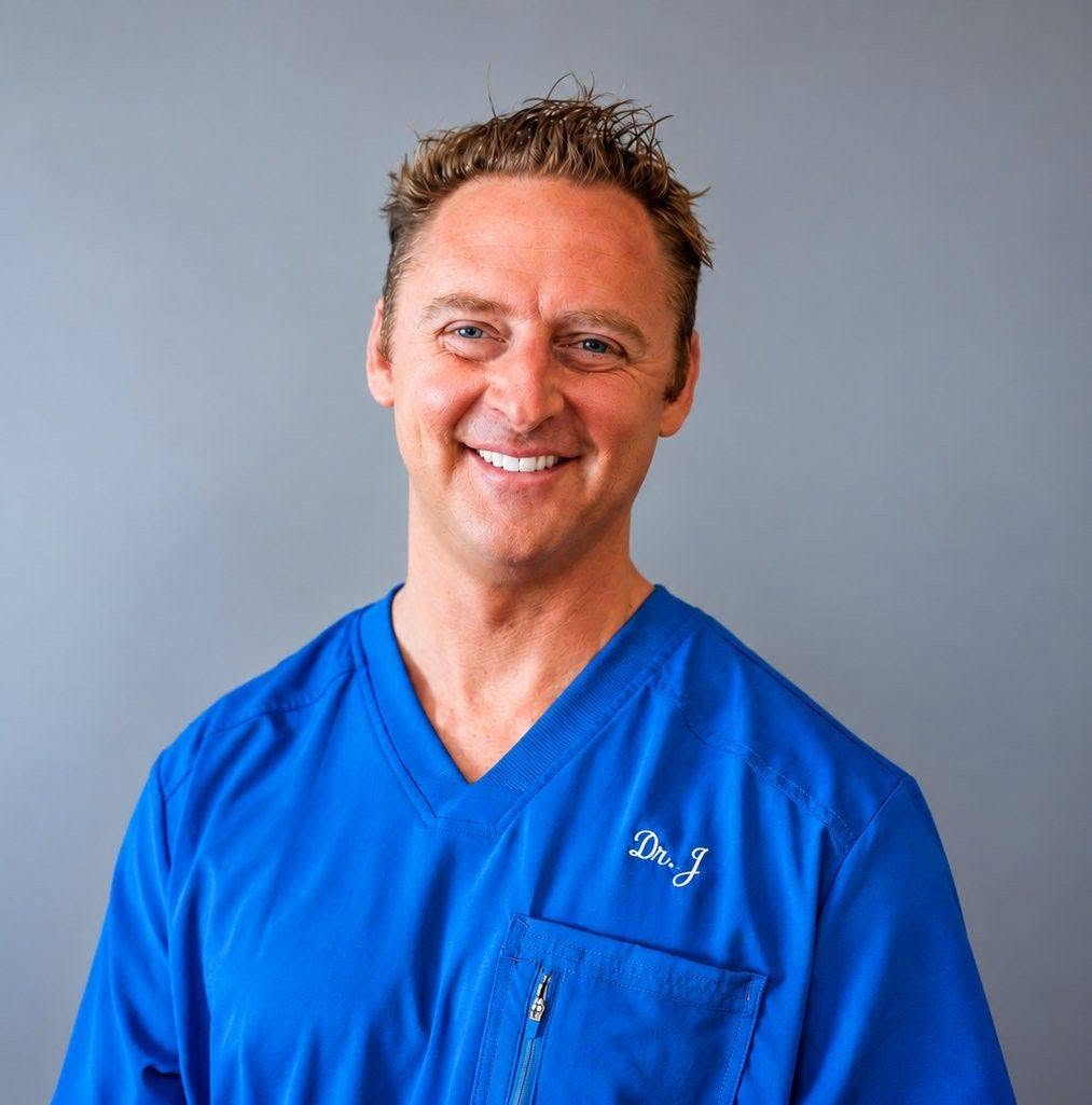 Headshot of a smiling man in blue scrubs with 'Dr. J' embroidered on the chest.